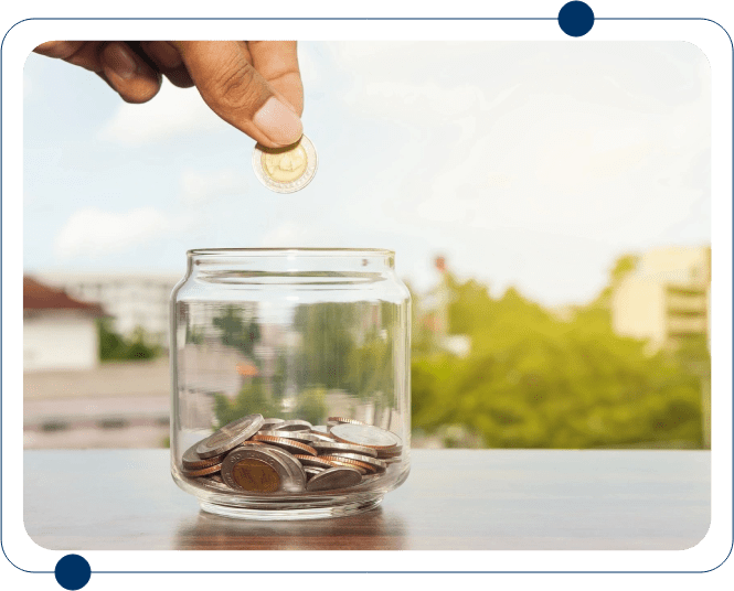 A person is putting money in a glass jar.